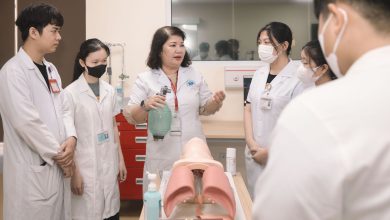 Grupo de estudantes de medicina pratica procedimentos com um manequim de treinamento em uma sala de aula.
