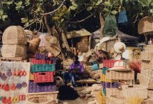 Cestos e outros artesanatos coloridos expostos para venda em uma feira ao ar livre.