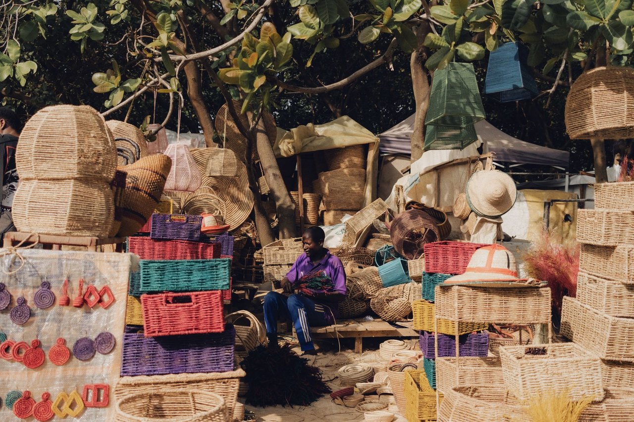 Cestos e outros artesanatos coloridos expostos para venda em uma feira ao ar livre.
