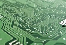 Detalhe de uma placa de circuito eletrônico com componentes, trilhas e um microprocessador.