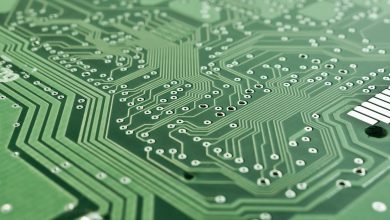 Detalhe de uma placa de circuito eletrônico com componentes, trilhas e um microprocessador.