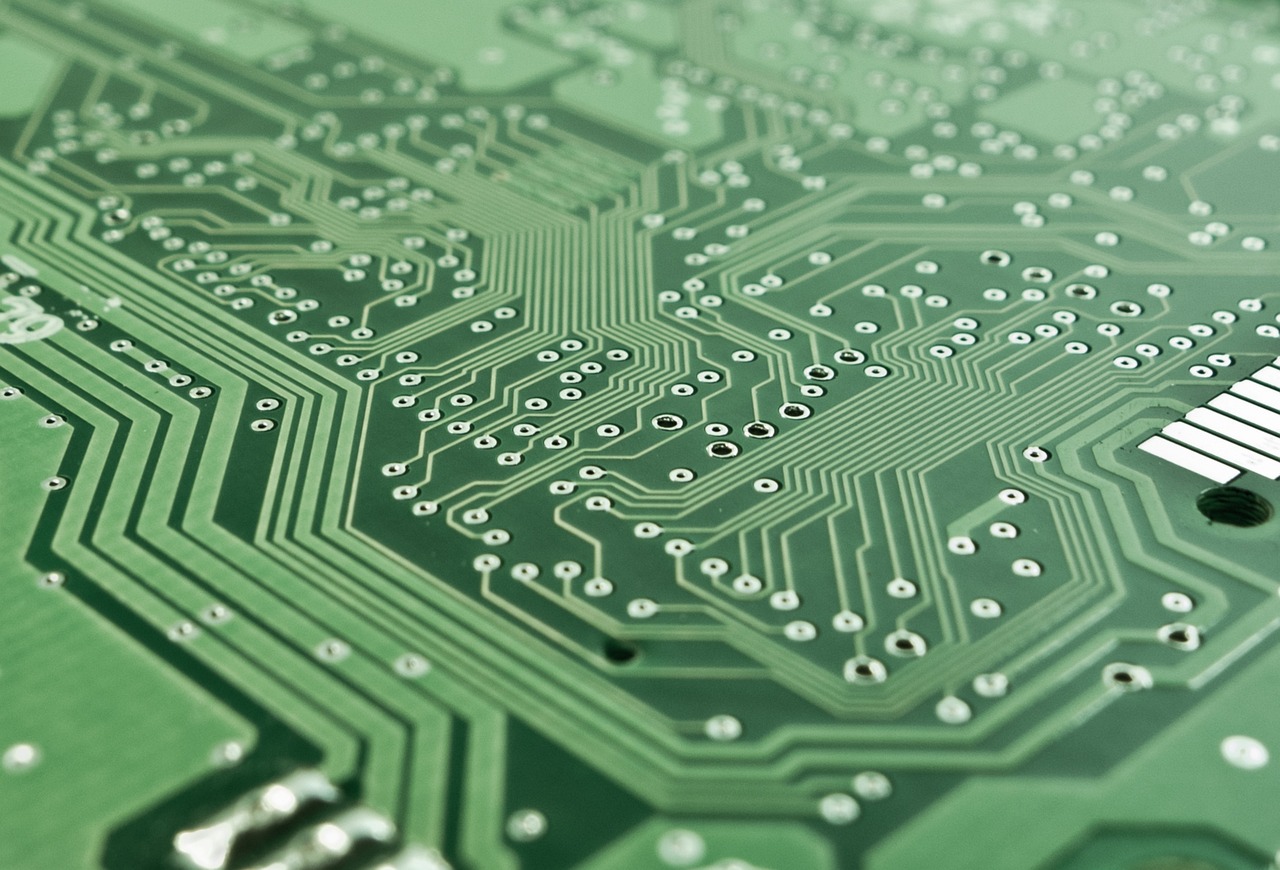 Detalhe de uma placa de circuito eletrônico com componentes, trilhas e um microprocessador.